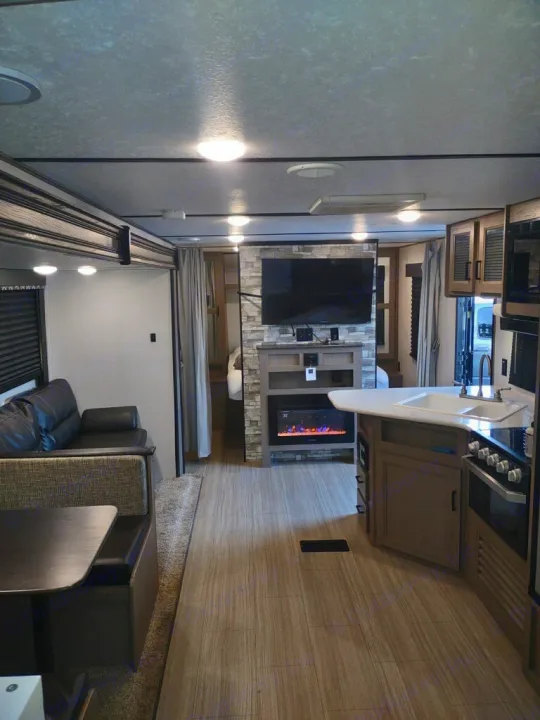 View inside an rv rental, highlighting a living space with TV/fireplace, dining, and kitchen area.. Keystone Hideout 2020