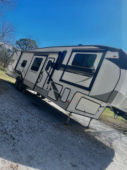 Modern white RV rental parked on gravel under clear blue sky, ready for adventure.. Coachmen Chaparral 2021