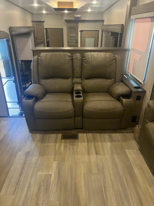 View inside an **rv rental**, featuring two comfortable reclining seats with cup holders, wood-look flooring, and built-in cabinetry.. Coachmen Chaparral 2021