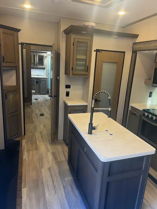 RV rental: Bright, modern kitchen with island and a spacious hallway leading to a bathroom.. Coachmen Chaparral 2021