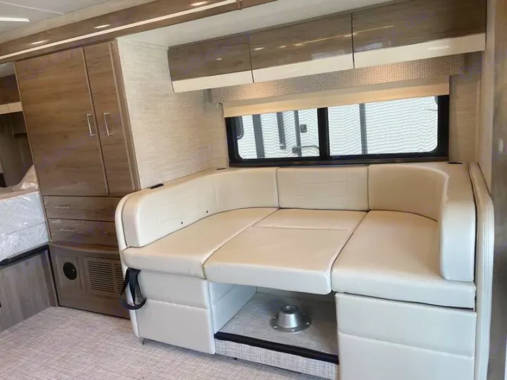 Spacious RV rental interior features a cream U-shaped convertible dinette, overhead cabinets, and large wardrobe storage.. Entegra Coach Qwest 24L 2024