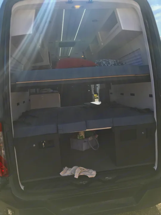 Interior of an **rv rental** camper van: bunk beds, lower seating/sleeping cushions, and integrated storage units.. Mercedes-Benz Sprinter 2022