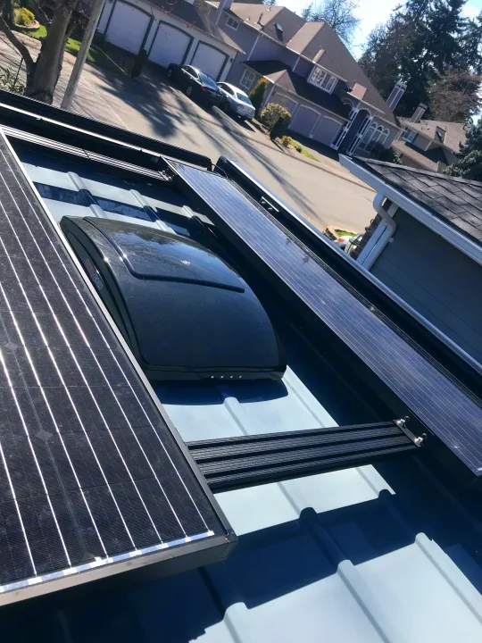 RV rental roof, featuring solar panels and a MaxxAir vent, parked on a residential street with houses in the background.. Mercedes-Benz Sprinter 2022