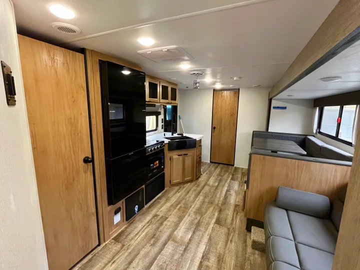 Explore this RV rental's spacious interior, featuring a full kitchen, dining area, and comfortable lounge seating.. Forest River Grey Wolf 29TE 2024