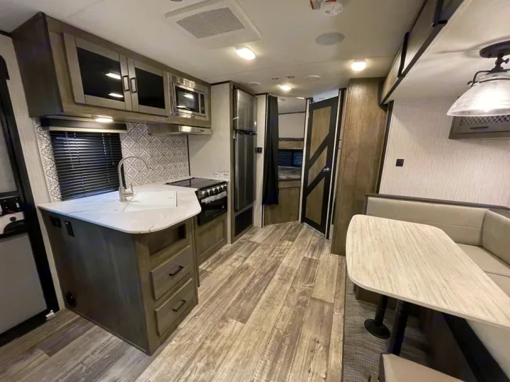 This RV rental features a full kitchen with white counters & patterned backsplash, a dining dinette, and bunks.. Heartland RVs North Trail 2021