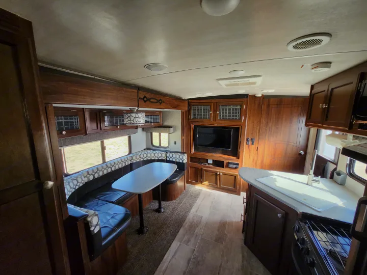 RV rental interior showcasing a U-shaped dinette, entertainment center with TV, and kitchen area.. Heartland Wilderness 2019