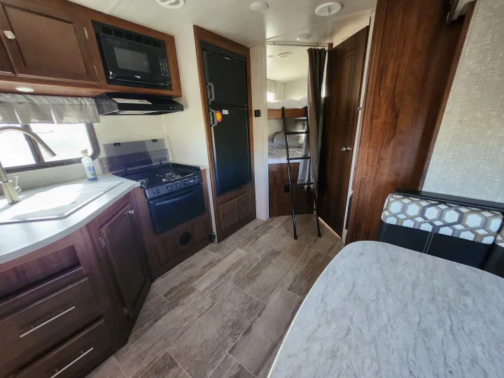 Spacious RV rental interior featuring a kitchen with appliances, dining area, and bunk beds. Ideal for travel adventures!. Heartland Wilderness 2019