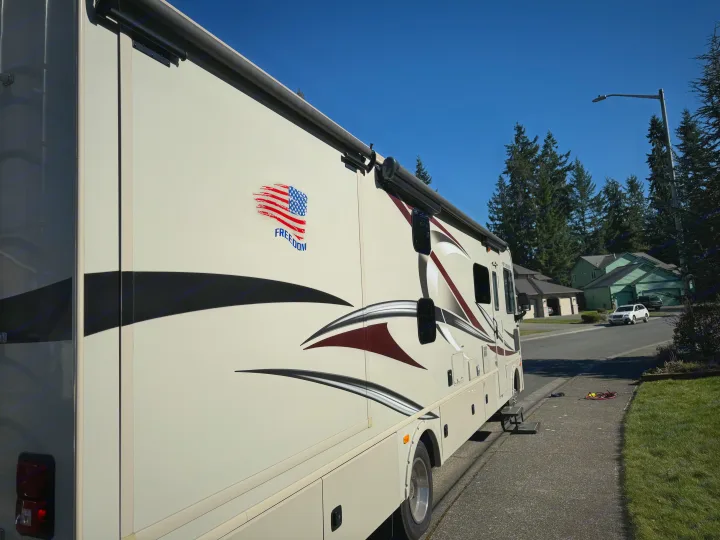 Inside this RV rental: a modern kitchen with stove, microwave & fridge, dining table, and cozy bunk beds beyond.. Flair-Fleetwood Flair-Fleetwood Motorhome 2017