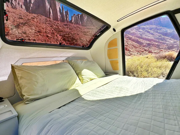 Cozy RV rental bed with stunning desert views from large windows, ideal for adventure travel in a comfortable camper.. Escapod Escapod Trailer 2023
