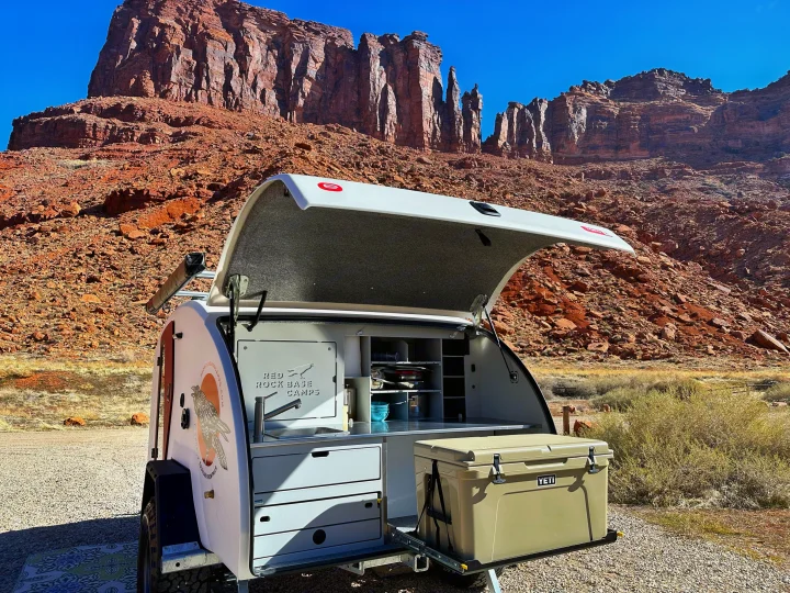 Red Rock Base Camps RV rental teardrop trailer with outdoor kitchen setup against stunning red rock desert landscape.. Escapod Escapod Trailer 2023