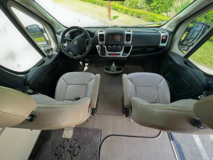 Spacious RV rental interior with swivel captain's chairs, dashboard, and a clear view outside.. Thor Sequence 2021