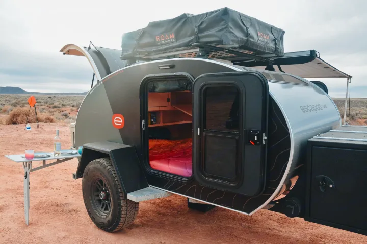 This Escapade teardrop camper, an ideal RV rental, offers adventure with its rooftop tent & outdoor setup in the desert.. Escapod Escapod Trailer 2022