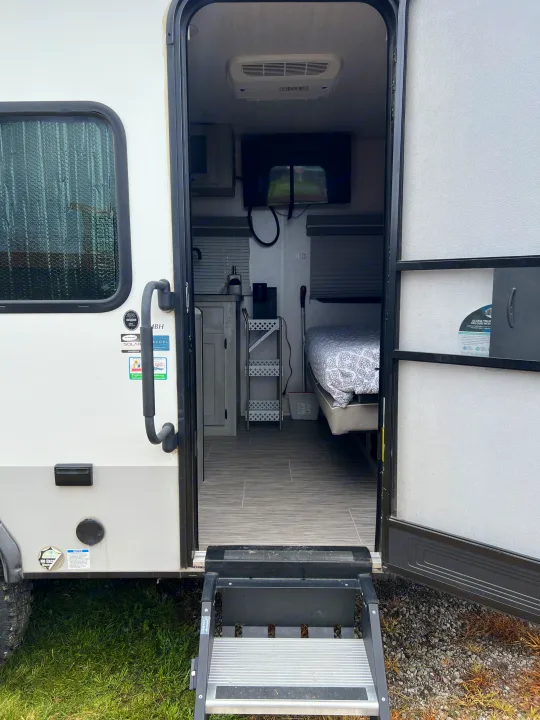 Step inside this cozy RV rental, revealing a compact interior with a bed, TV, and AC unit for comfortable travel.. Forest River Ibex 2021