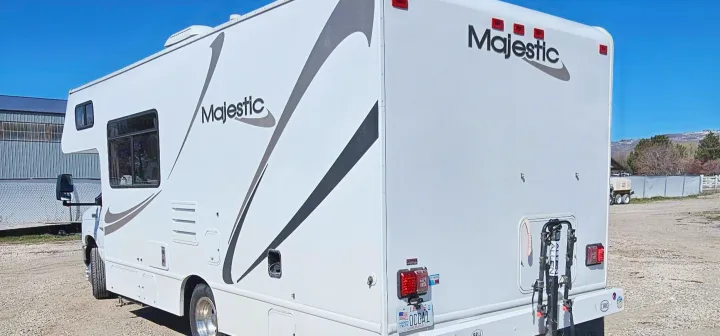 This white Majestic rv rental is parked outdoors, showcasing its side and rear with a bike rack, ready for adventure.. Thor Majestic 2014