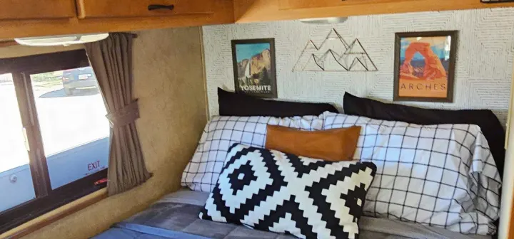 This RV rental bedroom features National Park art (Yosemite, Arches), wire mountain decor, and cozy bedding.. Thor Majestic 2014