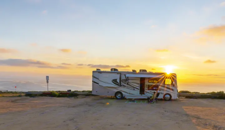 Stunning RV rental parked oceanside at sunset. People relax, soaking in the golden hour and sea breeze.. Fleetwood Fortis 2020