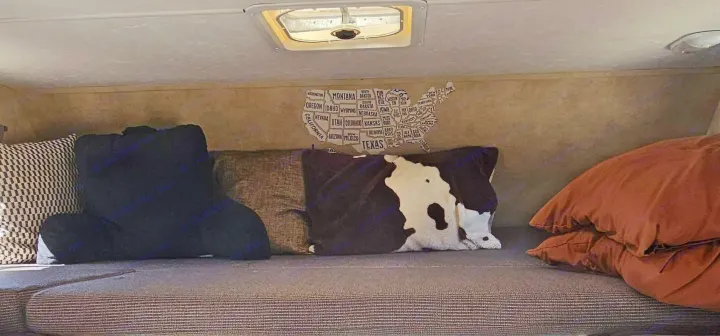 Cozy RV rental interior featuring a USA state map on the wall, multiple pillows on the bed, and a ceiling vent. Ideal for travel.. Thor Majestic 2014