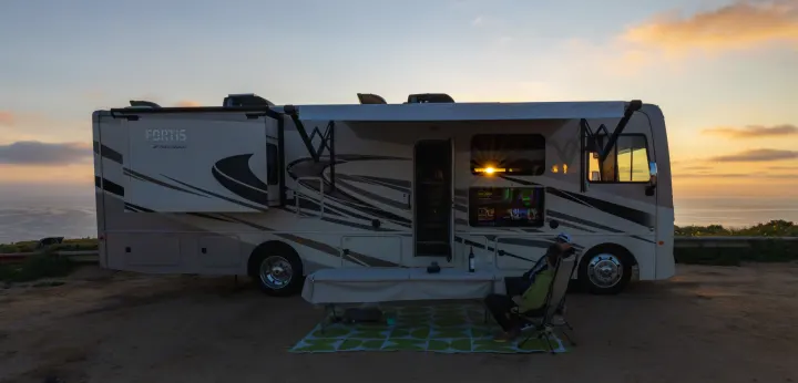 Relaxing RV rental sunset with stunning ocean views, outdoor entertainment, and a cozy campsite setup.. Fleetwood Fortis 2020