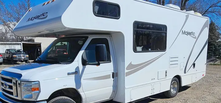 Spacious white Majestic RV rental, a Ford E-350 Super Duty motorhome parked on gravel, ideal for your next trip.. Thor Majestic 2014