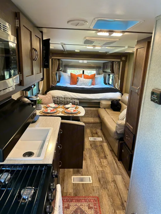 Bright RV rental interior: modern kitchen, dining area, and cozy bedroom, offering comfort and style for your next adventure.. Keystone RV Outback Ultra-Lite 2018