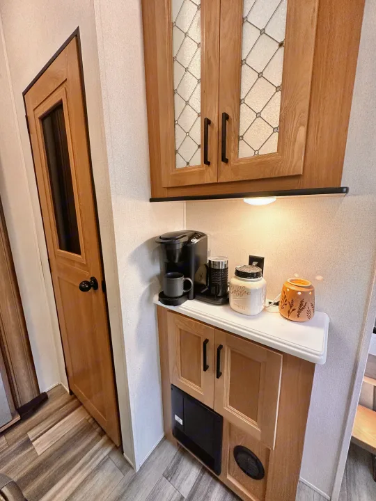 RV rental interior featuring a practical coffee station with a Keurig and frother, set amidst light wood cabinetry and a stylish wooden door.. Primetime Sanibel 3602WB 2023
