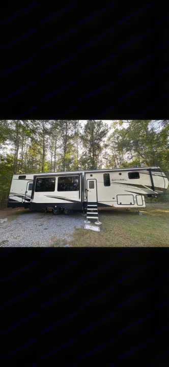 Cream Sanibel fifth-wheel RV rental with extended slides and steps, set up in a wooded campsite.. Primetime Sanibel 3602WB 2023