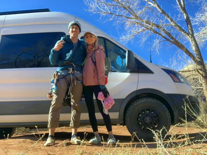 Happy couple by their adventure RV rental van, one with climbing gear, enjoying the sunny desert.. Ford Transit 2020