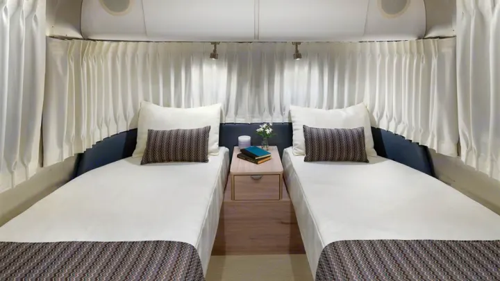 RV rental interior with two cozy twin beds, a nightstand, and individual reading lights for your trip.. Airstream Globetrotter 2020
