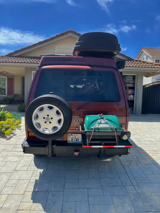 Back view of a maroon Westfalia camper van with spare tire, grill, and roof box, ready for your next rv rental adventure.. Volkswagen Westfalia 1987