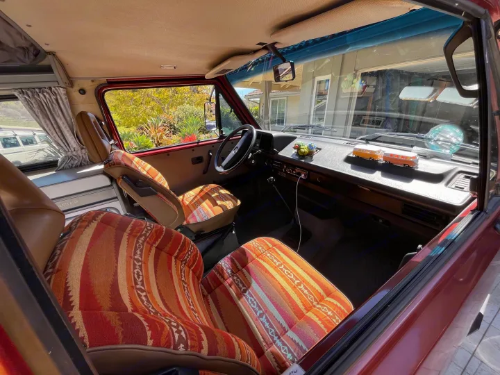 Interior view of a vintage VW Westfalia camper van, showcasing vibrant patterned seats. Perfect for your next RV rental.. Volkswagen Westfalia 1987