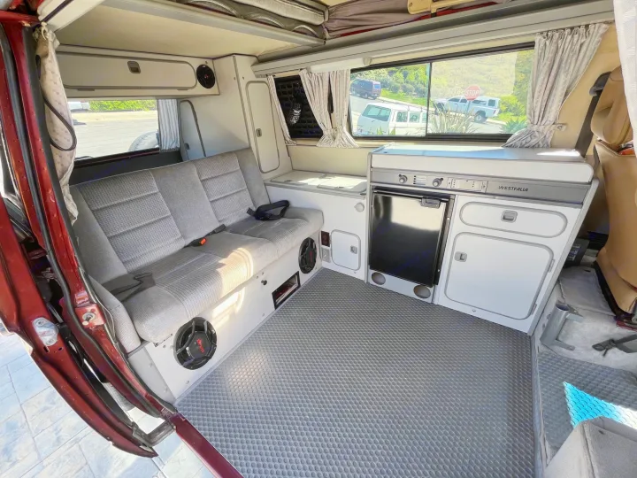 Pop-top Westfalia camper van interior ready for adventure, perfect for an RV rental. Features kitchen & seating area.. Volkswagen Westfalia 1987