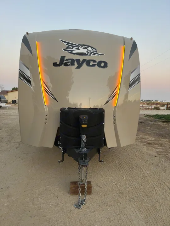 Front view of a tan Jayco travel trailer (RV) with orange LED accent lights. Perfect for an RV rental adventure, showing the hitch.. Jayco Eagle HT 2018