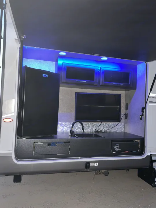 This RV rental's impressive outdoor kitchen features a mini-fridge, TV, sink, and blue LED lighting for camping fun.. Jayco Eagle HT 2018