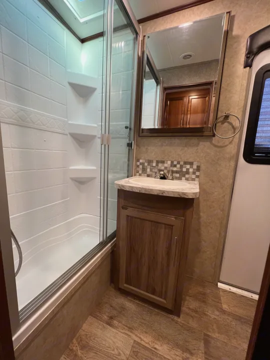 This RV rental features a modern bathroom with a glass-enclosed shower, vanity, sink, and mirror, designed for compact living.. Jayco Eagle HT 2018
