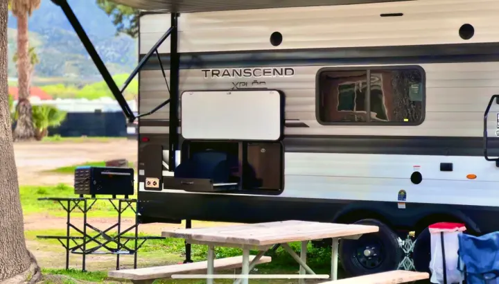 Enjoy the outdoors with this RV rental! Features an outdoor kitchen, picnic table, and grill at a scenic campsite.. Grand Design Transcend Xplor 2022