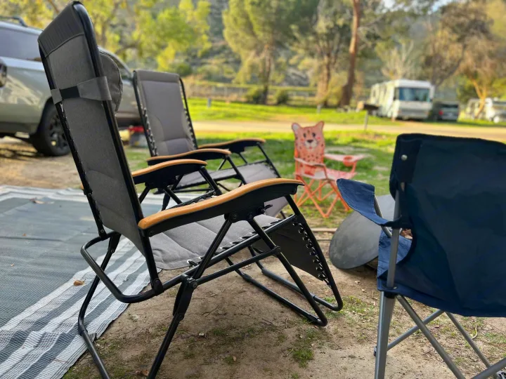 Comfortable camping chairs set up at an RV rental campground, with an RV and truck in the scenic background.. Grand Design Transcend Xplor 2022