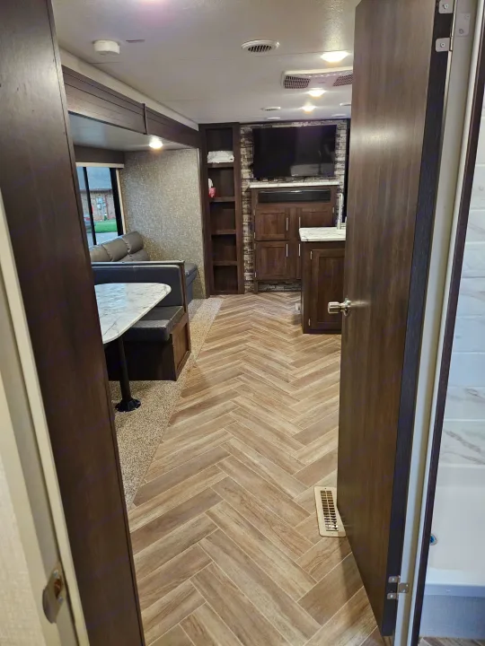 Spacious RV rental interior featuring a modern kitchen, cozy dinette, and stylish wood-look flooring.. KZ Sportsmen SE 2021