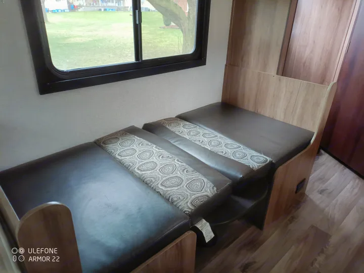 RV rental interior: dinette with dark cushions & patterned fabric by a window overlooking a green yard.. Jayco Hummingbird 2018