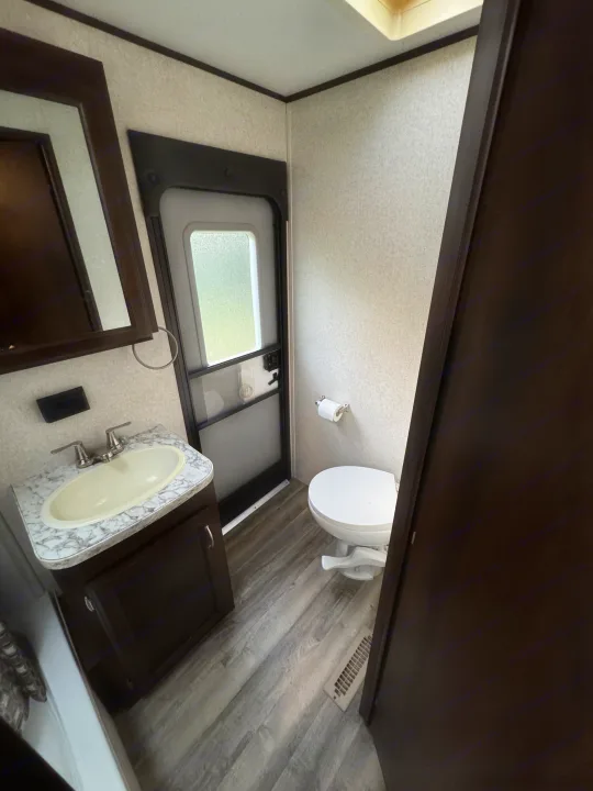 Compact RV rental bathroom featuring a sink, toilet, and a frosted glass door. Ideal for road trip comfort.. Jayco Jay Flight 2018