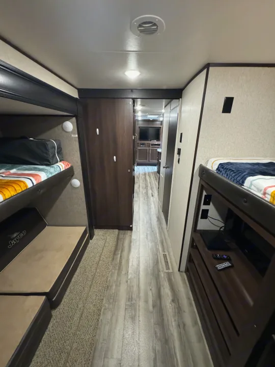 Inside a comfortable RV rental, showing a central hallway flanked by bunk beds and practical storage areas. Ideal for travel.. Jayco Jay Flight 2018