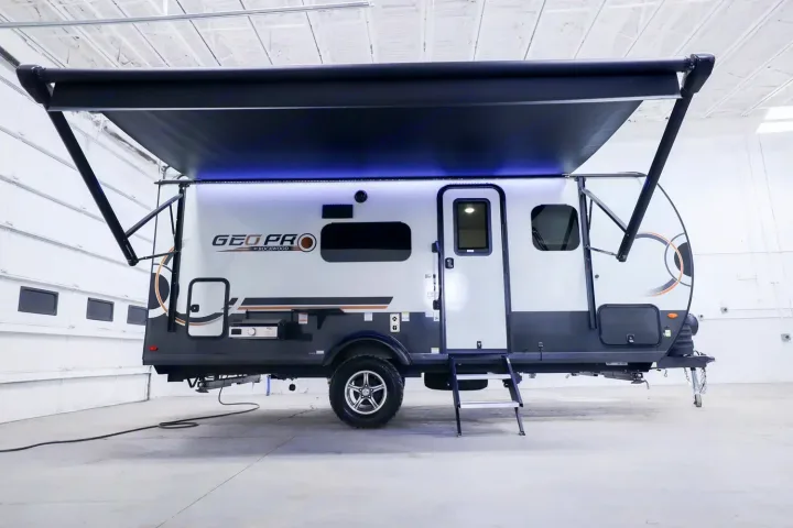 White & grey Geo Pro travel trailer RV rental with extended awning & illuminated exterior is ready for adventure.. Forest River Rockwood Geo Pro 2024