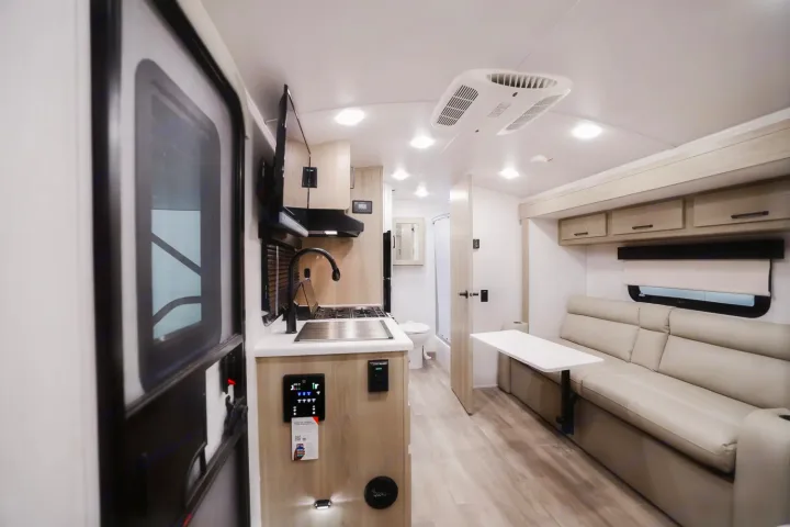 Step inside this RV rental's bright interior: full kitchen, comfy living area with sofa/table, and bathroom.. Forest River Rockwood Geo Pro 2024