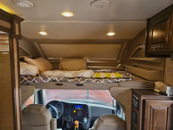 RV rental interior showing comfortable bunk over cab sleeping area and driver's cockpit.. Entegra Coach Accolade XL 2021