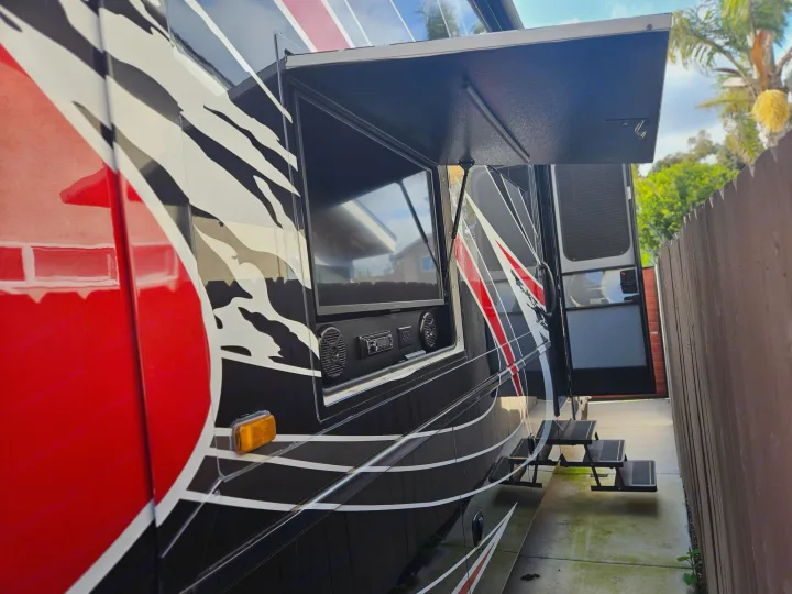 This RV rental features an open outdoor entertainment center with TV, speakers, and pull-out steps.. Entegra Coach Accolade XL 2021