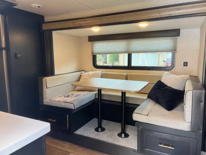 Inside a cozy **RV rental**: a dinette area with built-in booth seating, a table, and ample storage drawers.. Forest River Cherokee Wolf Pup Black Label 2022