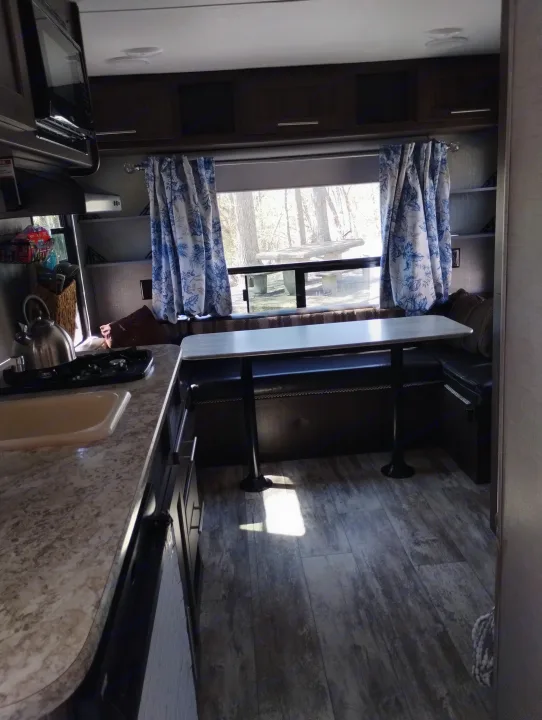 RV rental interior featuring a practical kitchen area, comfortable dinette, and bright window view of a campsite.. Crossroads RV Z-1 Lite 2018