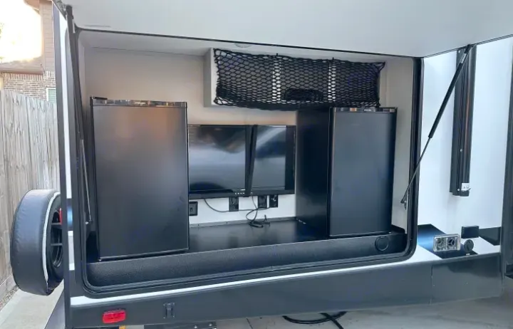 This RV rental features a cleverly designed outdoor entertainment & kitchen area with two mini-fridges and monitors.. Forest River Vibe 2022