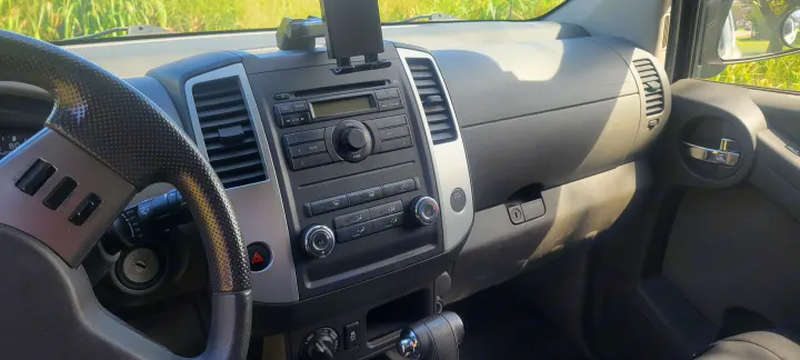 Interior of a vehicle dashboard with steering wheel and controls, ideal for an RV rental road trip adventure.. Nissan Xterra 2012