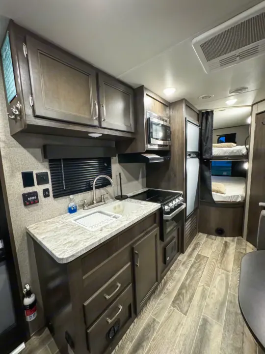 Inside a stylish RV rental: fully equipped kitchen, bunk beds, and modern design. Perfect for your next adventure!. Jayco Jay Flight SLX 2021