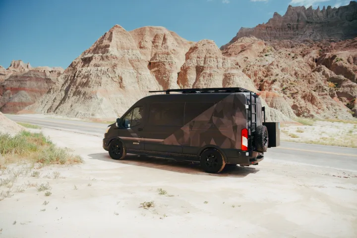 Adventure-ready rv rental: A custom geometric-patterned camper van is parked on a sandy shoulder amidst majestic Badlands peaks.. Vandoit Vandoit Class B 2020